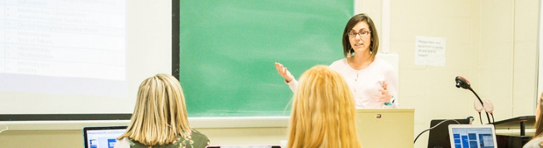 Instructor indicates to lesson on chalkboard in front of class
